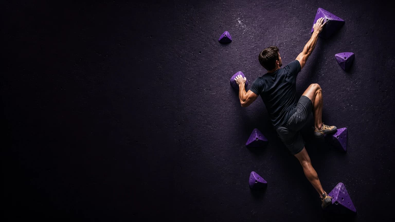 A climber keeps hips close, one foot precise, and one arm long on a violet bouldering wall